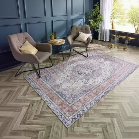 Patterned rug on a wooden floor with two chairs and a small table in a room.