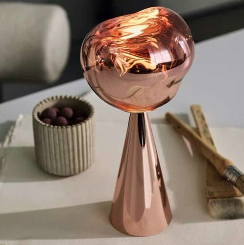 Rose gold decorative object on a surface with a blurred background
