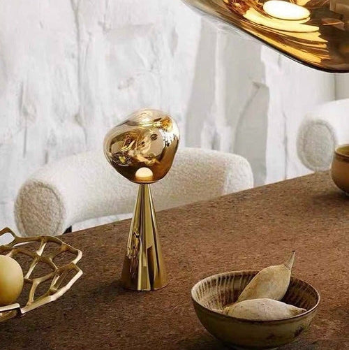 Gold decorative object on a wooden table with a marble wall background