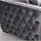 Gray tufted velvet armchair on a light gray floor.