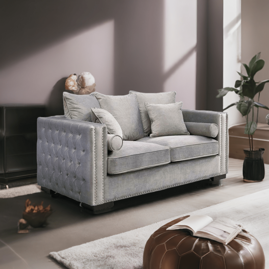 Gray tufted sofa in a modern living room with a plant and ottoman.