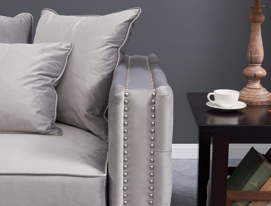 Gray sofa with decorative pillows and a wooden side table with a cup in a room.
