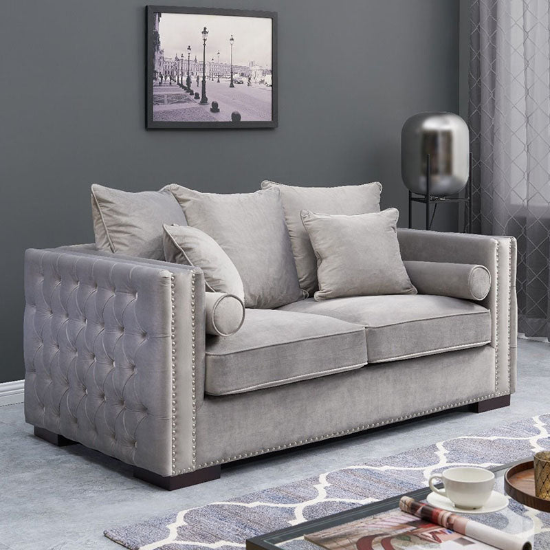 Gray tufted sofa in a living room with a coffee table and decorative items.