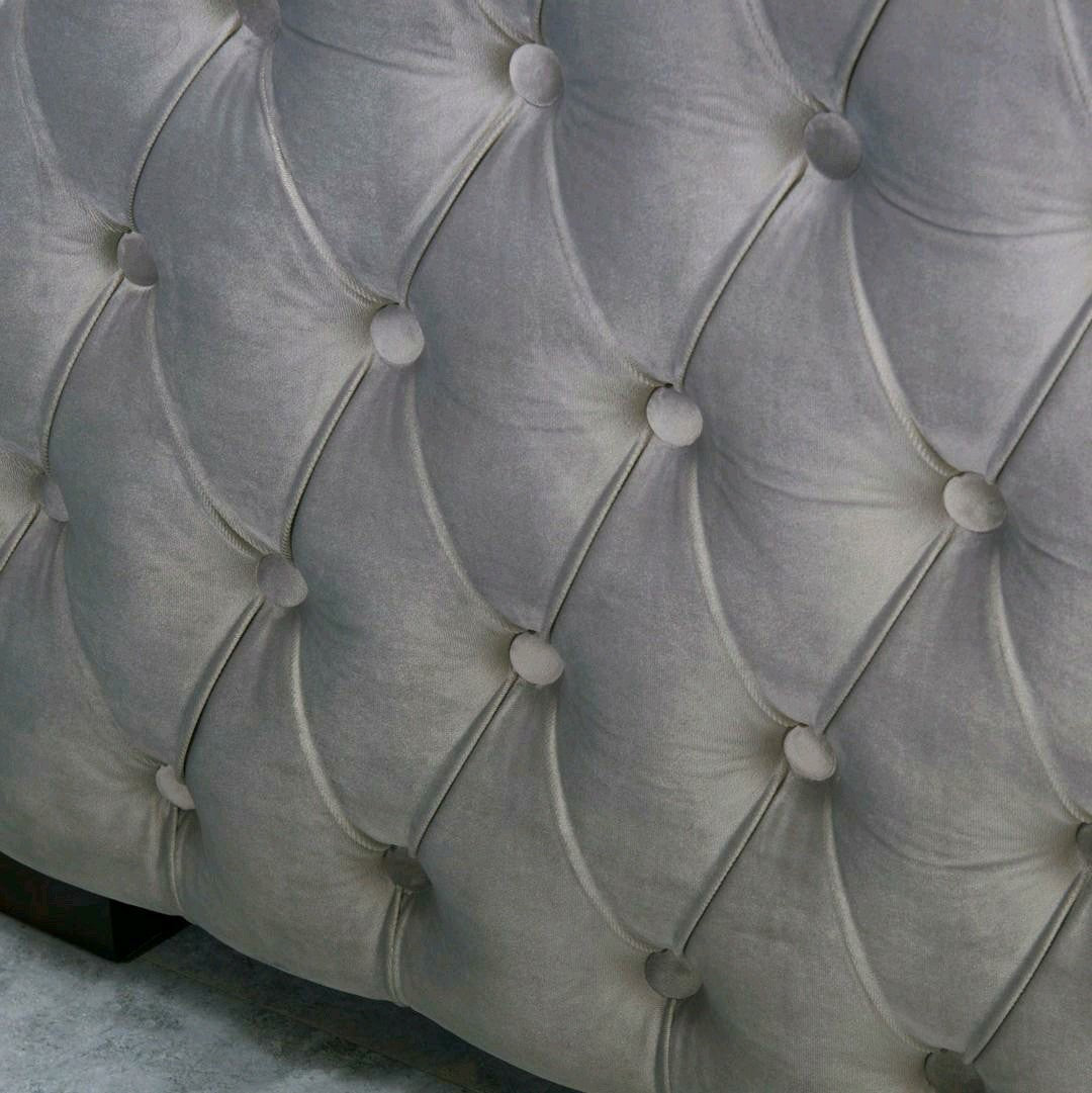 Close-up of a tufted gray upholstered headboard
