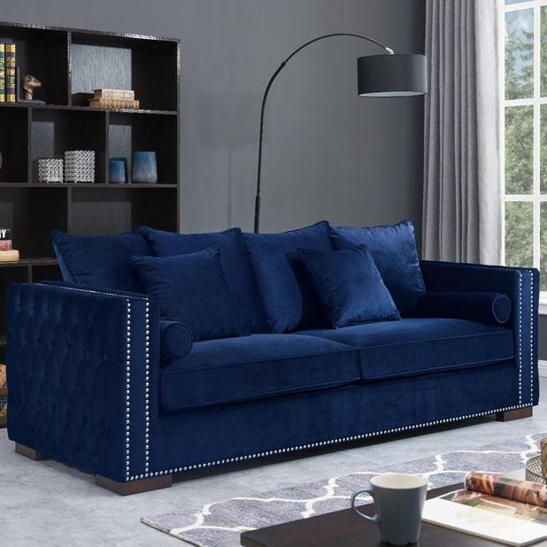 Blue sofa in a living room with a bookshelf and lamp.