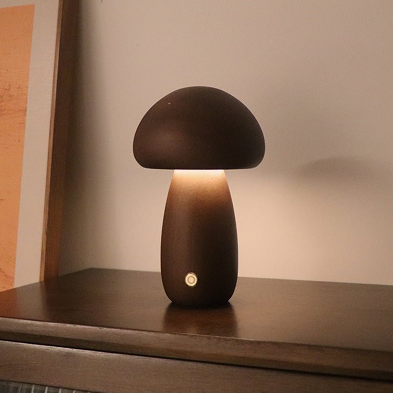 A collection of mushroom-shaped wood lamps in various colors illuminated, displayed on a shelf.