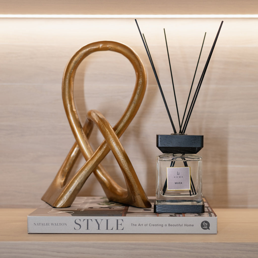 Decorative diffuser with gold sculpture and book on a wooden surface