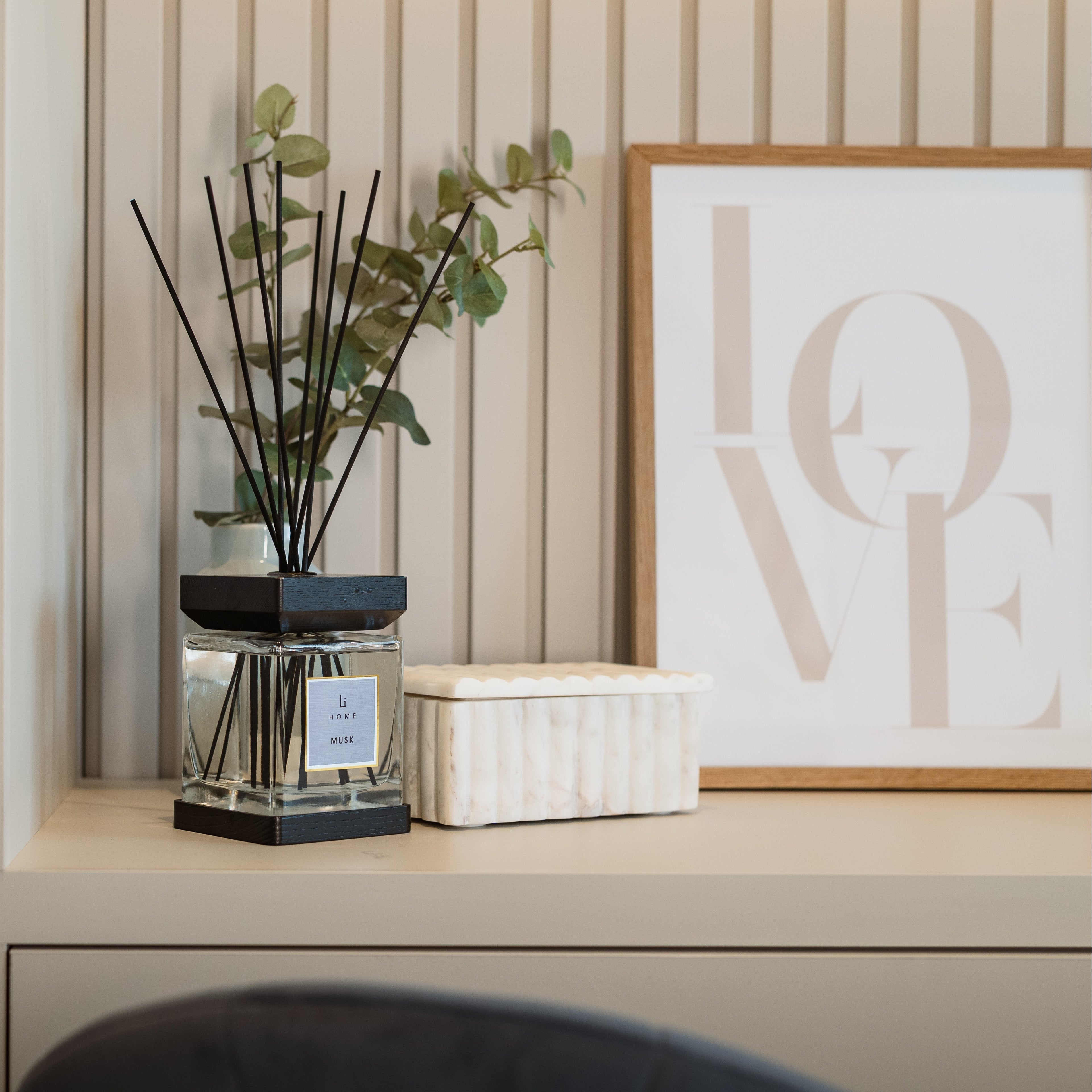 Decorative shelf with a diffuser, plant, and framed 'LOVE' artwork.