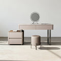 Beige vanity table with mirror and stool in a minimalistic room.