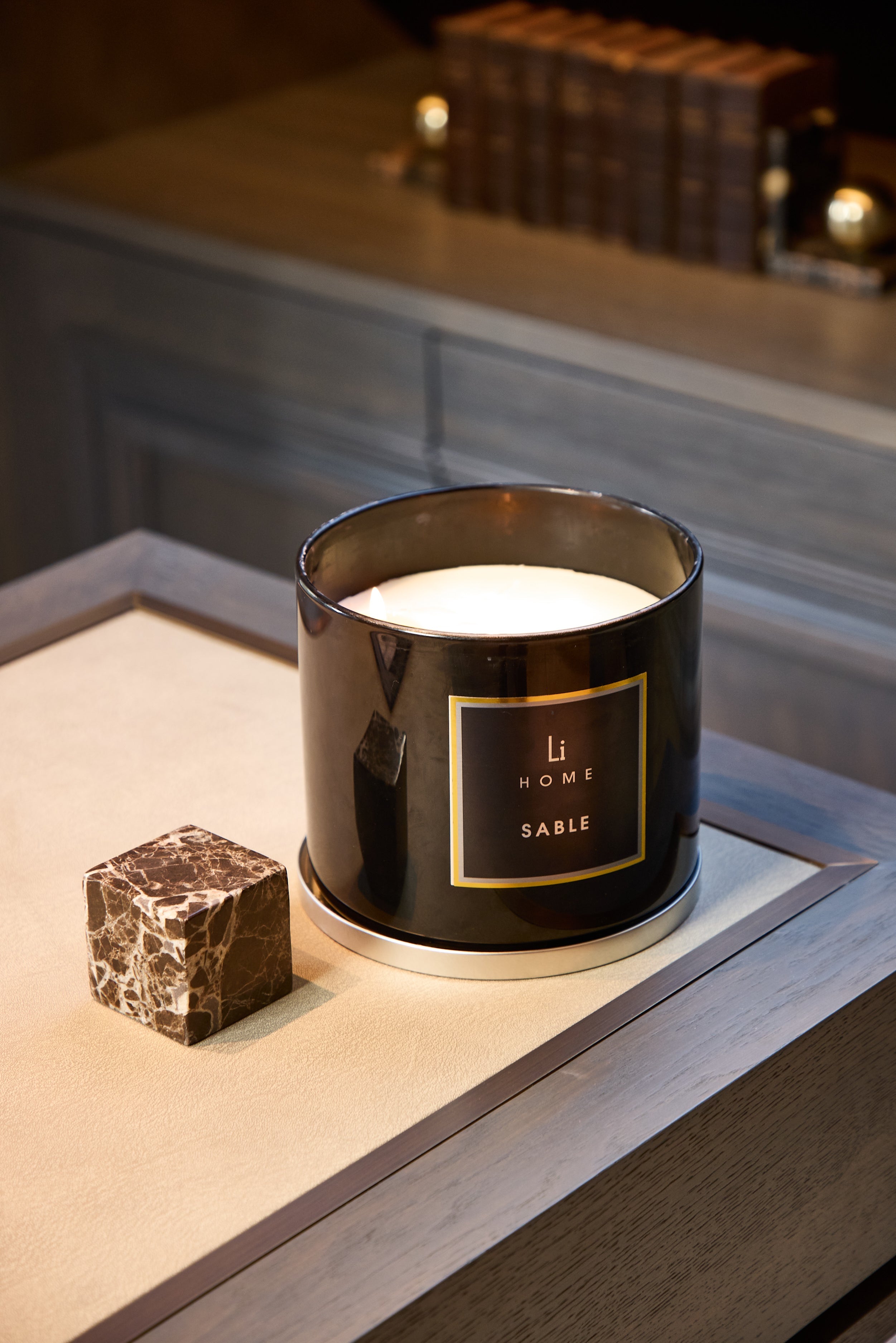 Black candle labeled 'Sable' on a wooden surface with a blurred background