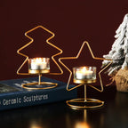 Gold wire tree and star candle holders with lit candles on a dark surface.