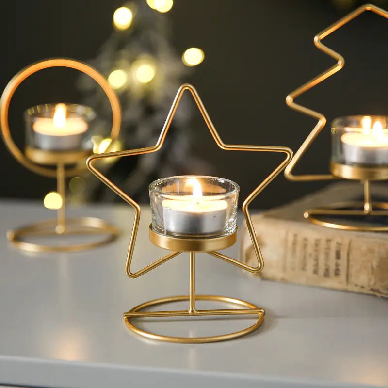Gold star-shaped candle holders with lit candles on a reflective surface.