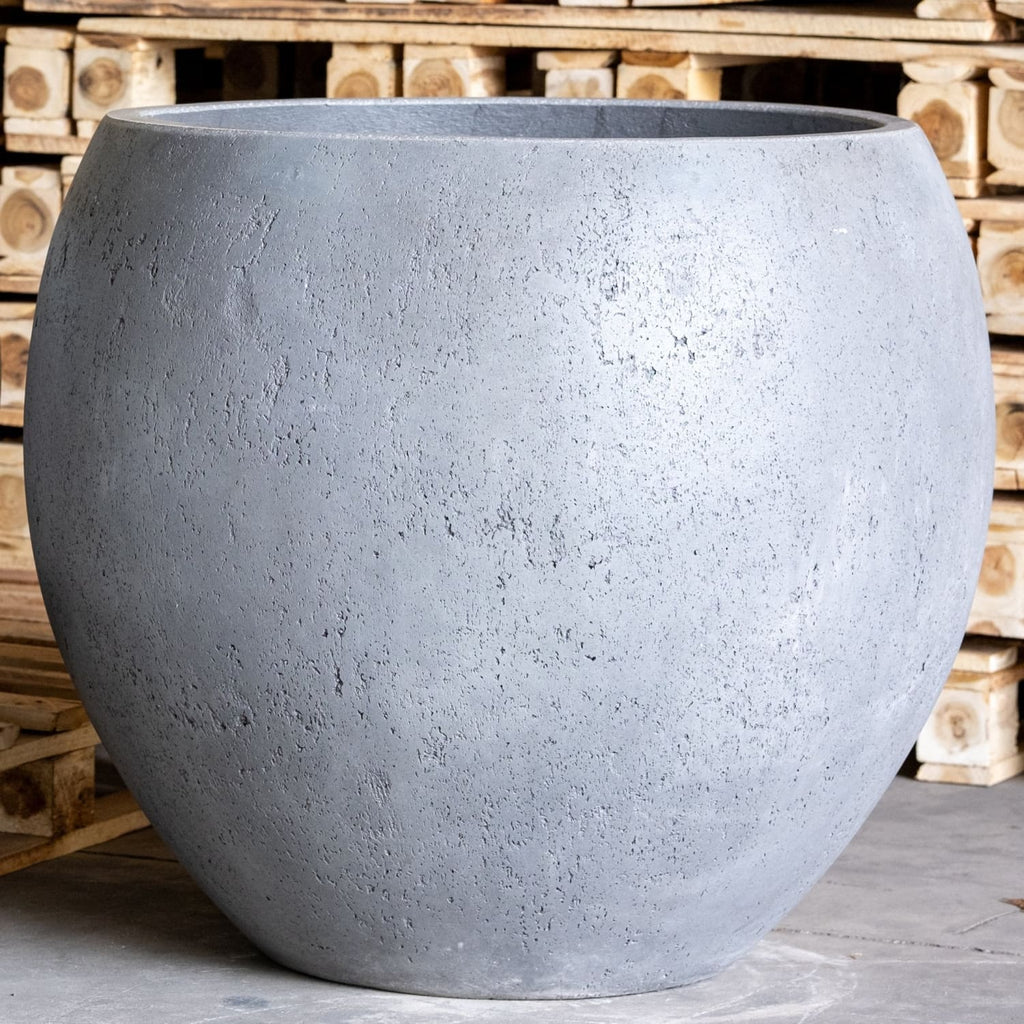 Large gray concrete pot in front of wooden pallets