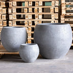 Three gray concrete planters of different sizes on a wooden pallet background