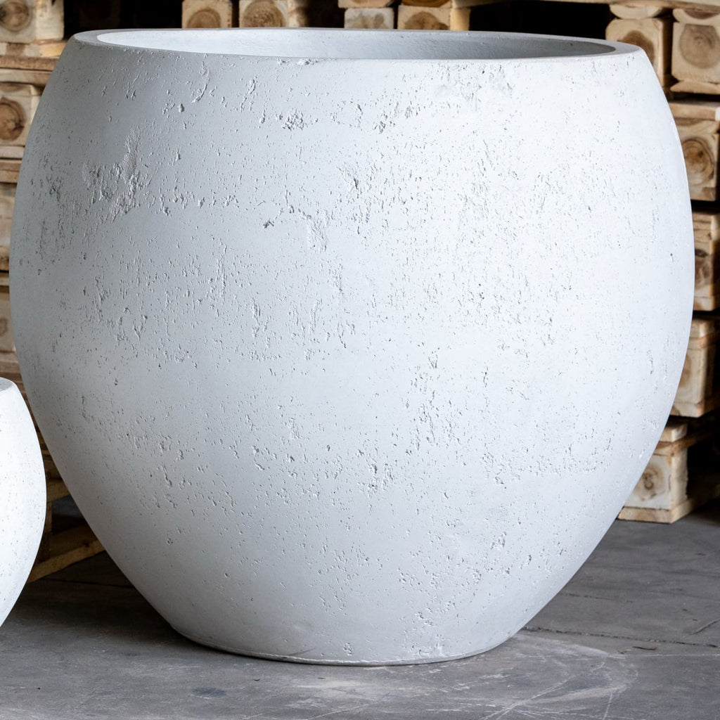 Large white concrete planter in front of wooden pallets
