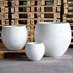 Three white concrete planters of different sizes on a wooden pallet background