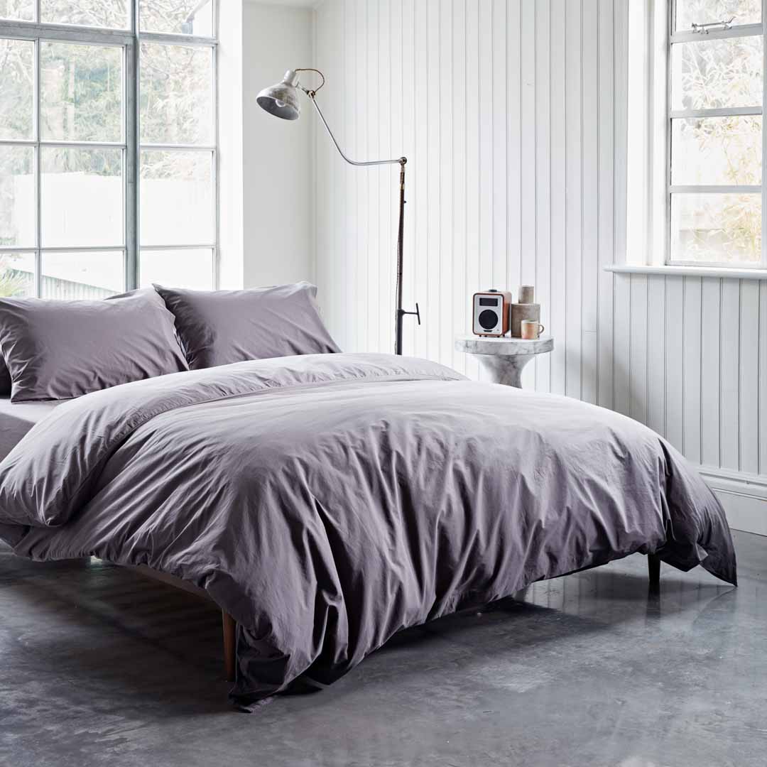 Bedroom with gray bedding and a lamp in a bright room