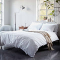 Neatly made bed with white bedding in a bright bedroom.
