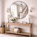 Console table with decorative items in a room with a large round mirror above it.