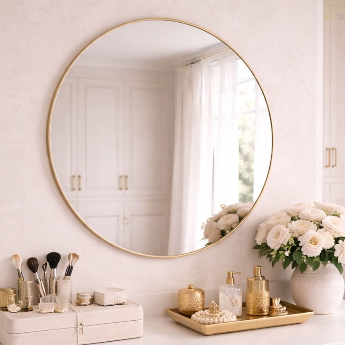 Round gold-framed mirror on a white wall with decorative items below.