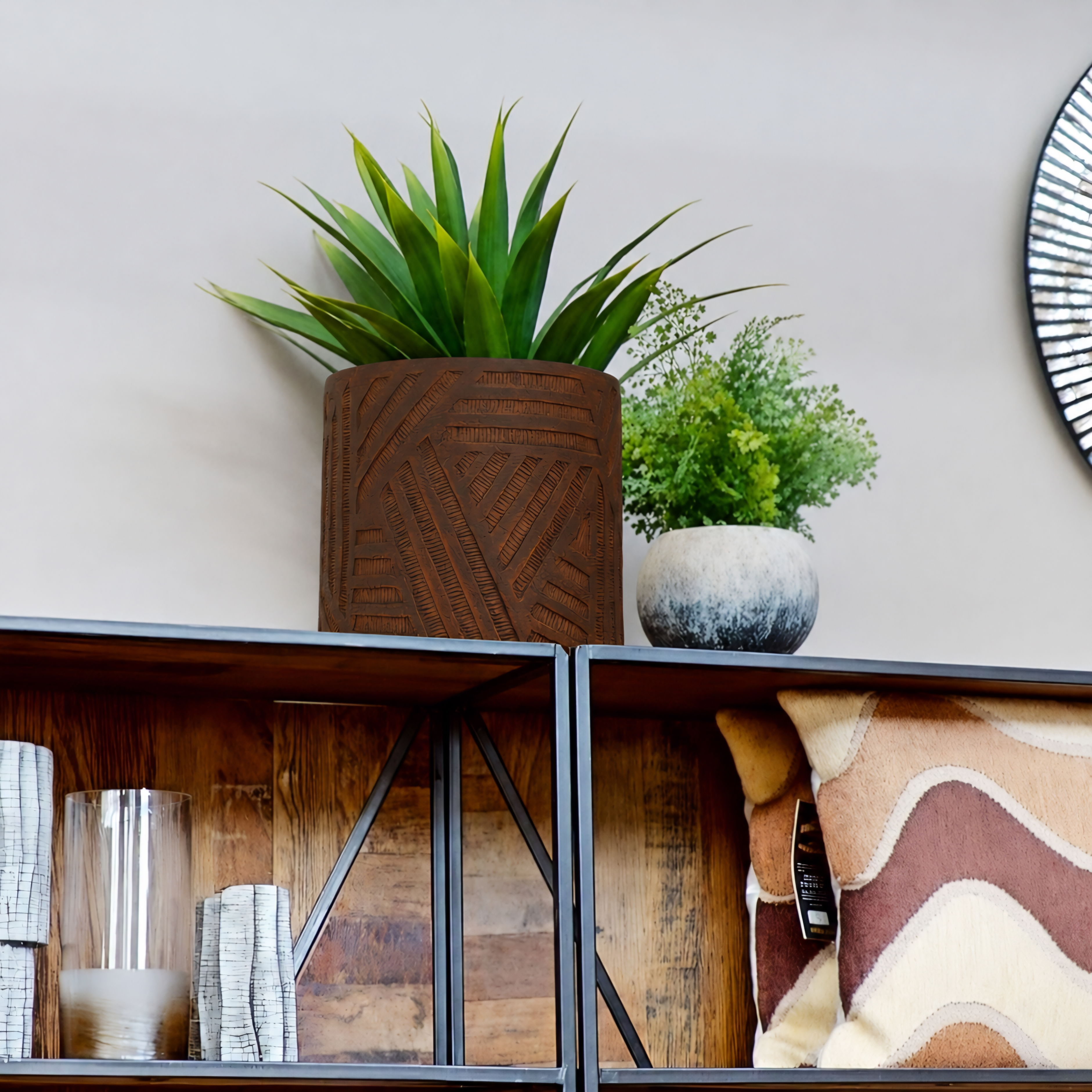Decorative potted plants displayed on a wooden shelf in a home setting, featuring a tall green succulent in a textured brown pot and a smaller green plant in a gray pot.