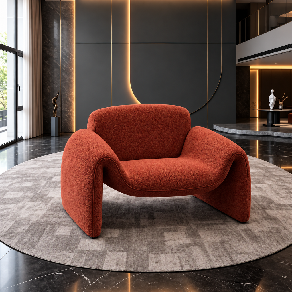 Sculptural curved armchair in textured rust-orange fabric on a round rug in a modern luxury interior with dark walls and warm lighting.