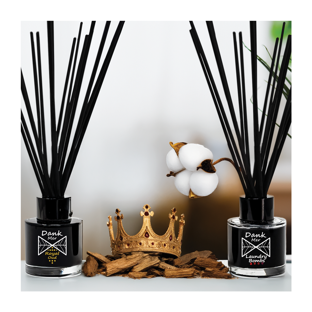 Two diffuser bottles with black sticks and cotton, a gold crown, and wooden elements on a white background.