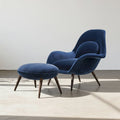 Blue armchair with matching ottoman on a light floor and white wall background