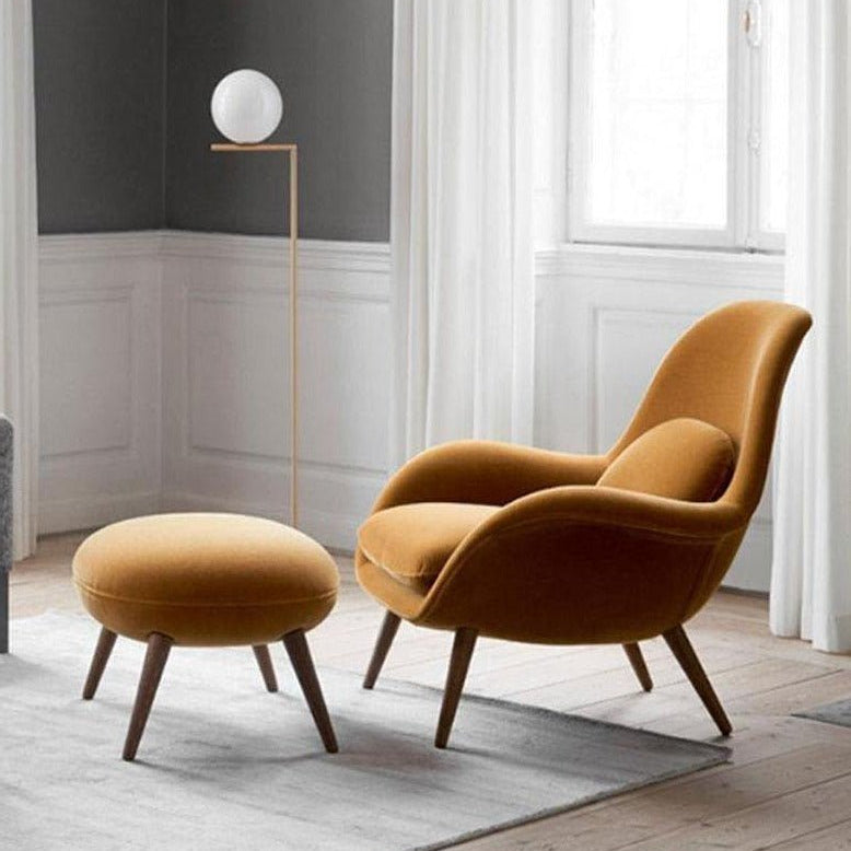 Mustard yellow armchair and ottoman in a room with a lamp and window.