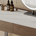 Wooden vanity with a white countertop, decorative bottles, and a round mirror.