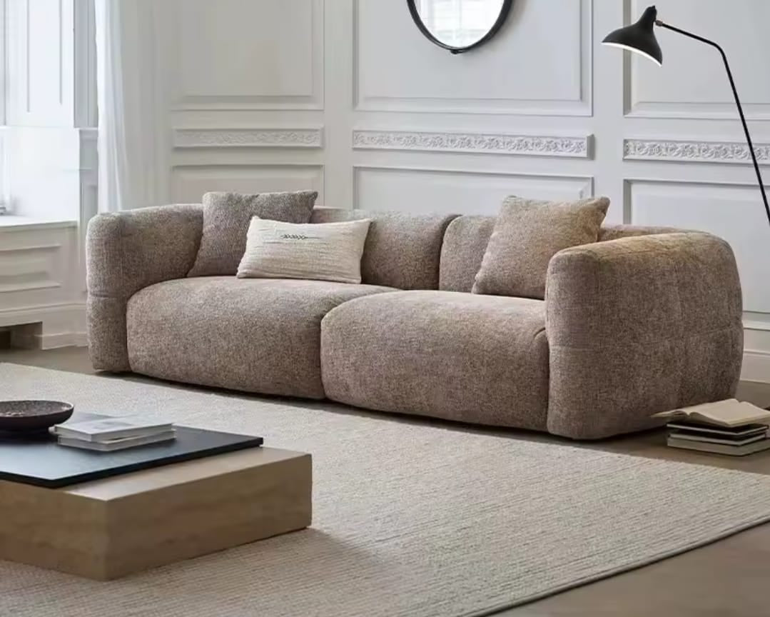 Beige sofa in a modern living room with a coffee table and decorative items.
