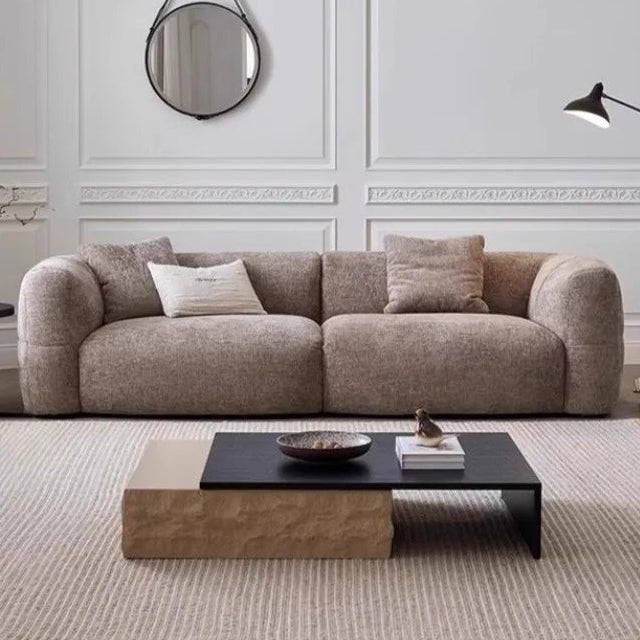 Modern living room with a beige sofa, coffee table, and decorative items.