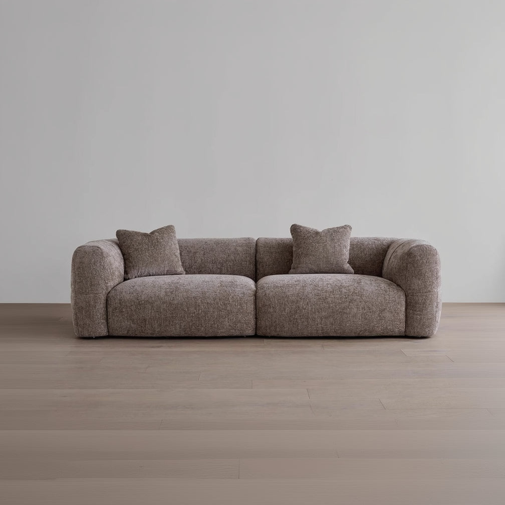 Brown sofa with two cushions on a wooden floor and gray wall background