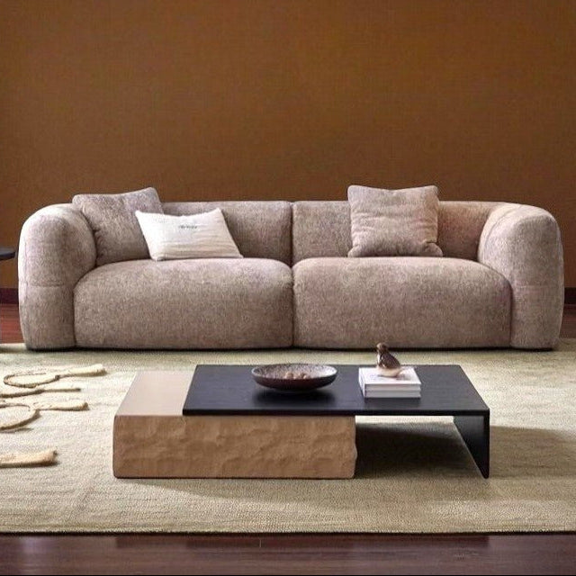 Beige sofa in a living room with a coffee table and decorative items.