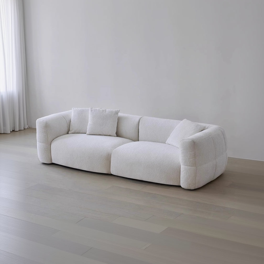 White sofa with cushions on a light wooden floor and white wall background