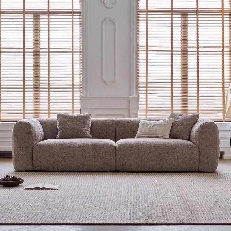 Gray sofa with cushions in a room with wooden blinds