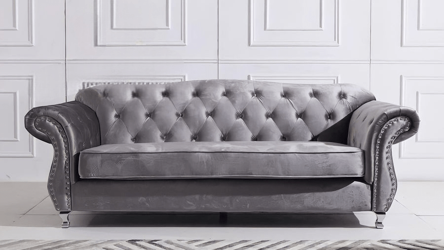 Gray tufted sofa in a room with white paneled walls.