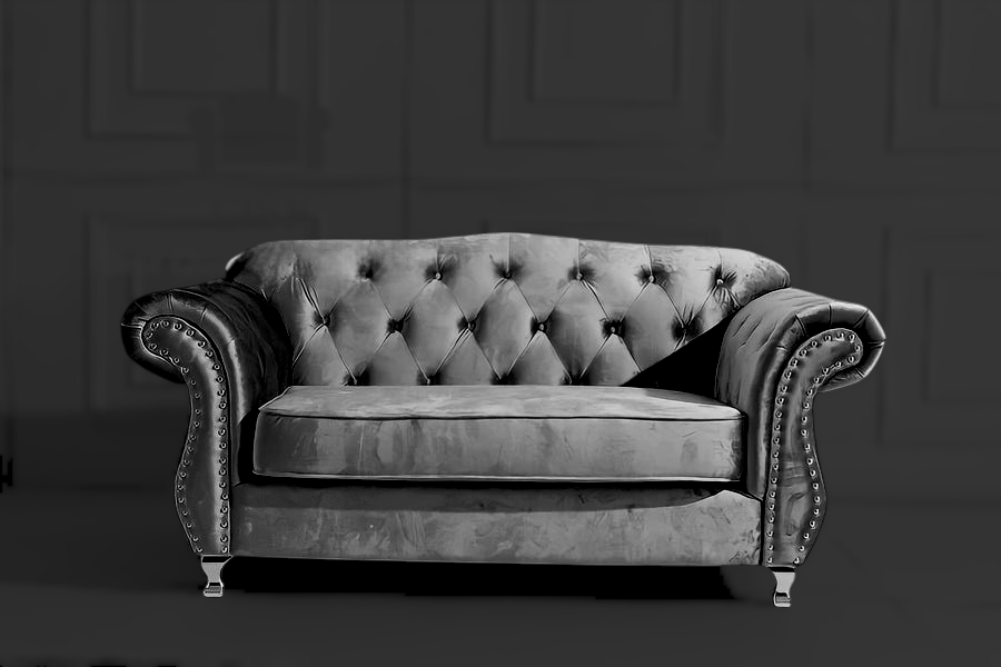 Gray velvet sofa with buttoned backrest in a dark room