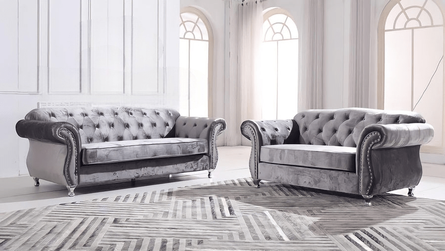 Two gray velvet sofas in a room with large windows and a patterned rug.