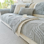 Gray textured sofa cover on a beige sofa with cushions and a cup.