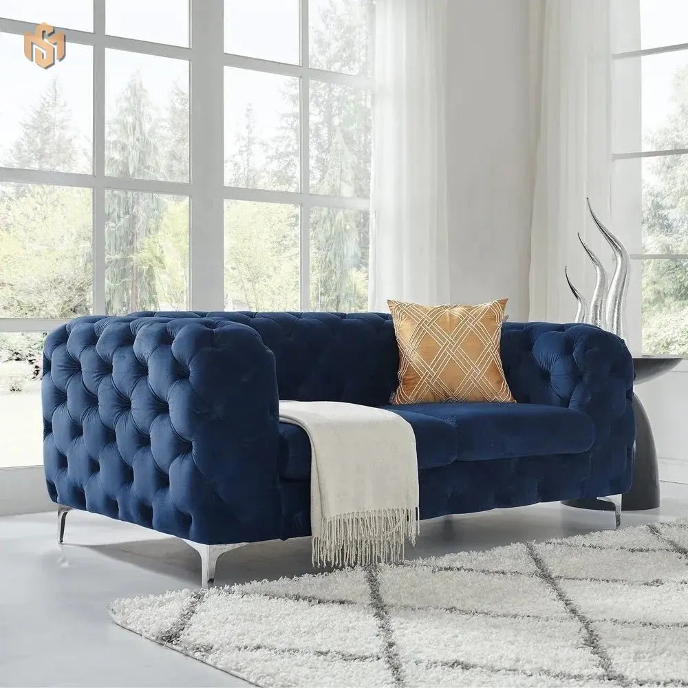 Blue tufted sofa with a gold pillow and white blanket in a bright room.