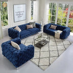Blue velvet sofa set in a modern living room with a geometric rug and glass coffee table.
