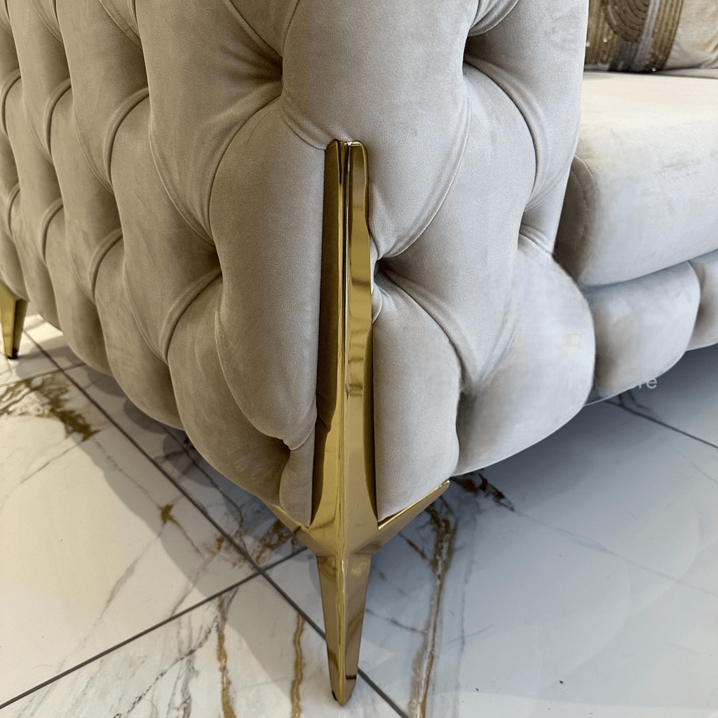 Beige tufted sofa with gold legs on a marble floor