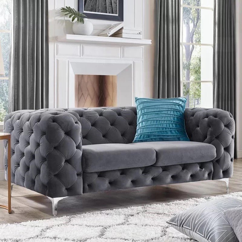 Gray tufted sofa with a blue pillow in a living room setting.