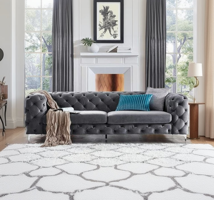 Gray tufted sofa with a blue pillow in a living room setting.