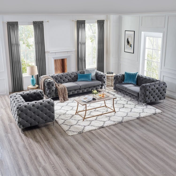 Gray tufted sofa set in a living room with a coffee table and decorative items.