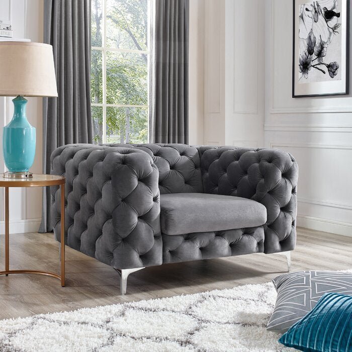 Gray tufted sofa in a living room with a lamp and decorative pillows.