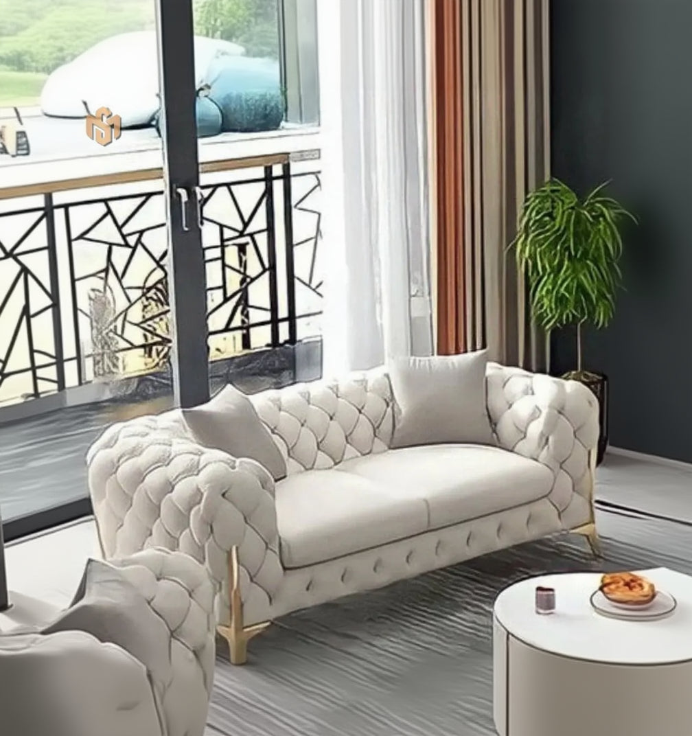 Modern living room with a tufted white sofa, round coffee table, and decorative elements.