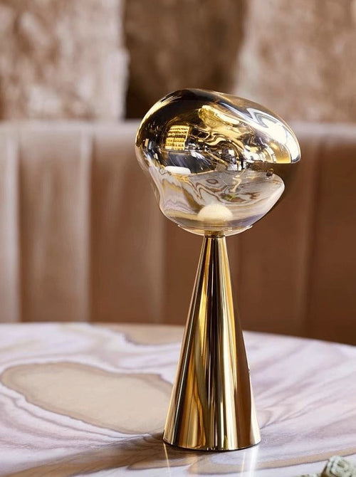 Gold and clear decorative object on a marble surface with a blurred background