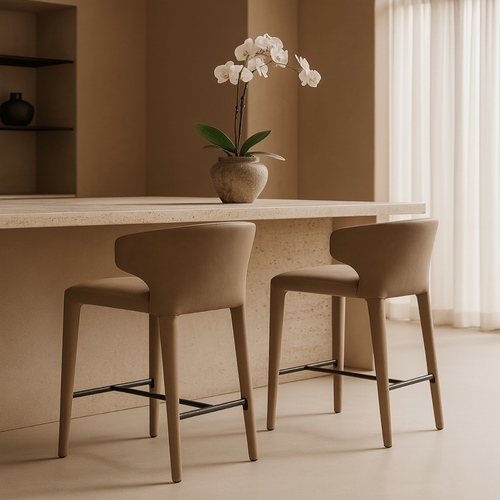 Two beige bar stools in front of a light-colored counter with a vase of white flowers on a neutral background.